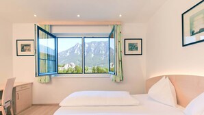 A bedroom with a bed, a desk, and a window with curtains. - Flackl - Wirt  (Reichenau an der Rax)