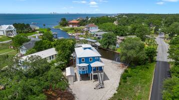 A residential area with a prominent blue house featuring a front porch and a staircase leading to a deck.