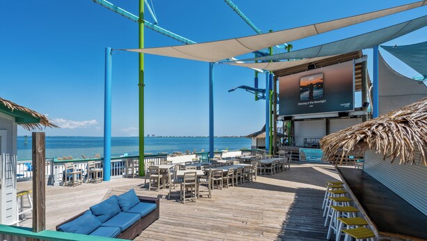 Um terraço com área de estar ao ar livre, um bar e vista para o oceano.