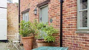 A brick building with a number '5' sign, a door, and two potted plants. - Templar Mews, heart of town (Cirencester)