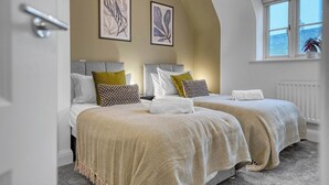 A bedroom with two beds, a window with a view, and artwork on the wall. - Discounts for Extended Stays - sleeps 4 (Gloucestershire)