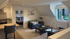 A compact living space with a kitchenette, a dining area, a sofa, a coffee table, and a window with a view.