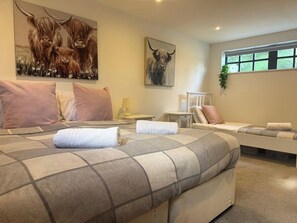 A hotel room with a large bed, a bedside table, a chair, and a window with a view. - The Carriage House, peaceful, beautiful cottage (Gloucestershire)