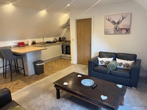 Een compact verblijf met een kitchenette, een eethoek en een zithoek met een bank en salontafel.