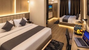Una habitación de hotel moderna con dos camas, un escritorio con una computadora portátil, un ventilador de techo y un televisor.