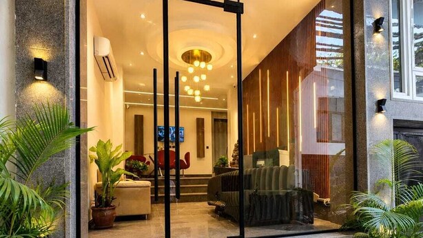 Un interior moderno con entrada de vidrio, una escalera que conduce a la entrada y plantas de interior.