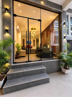 Un interior moderno con entrada de vidrio, una escalera que conduce a la entrada y plantas de interior.