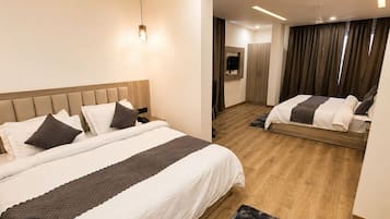A modern hotel room with a large bed, a smaller bed, a ceiling fan, and a TV.