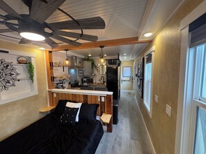 Een moderne keuken met een centraal eiland, een houten plafondventilator en hanglampen.