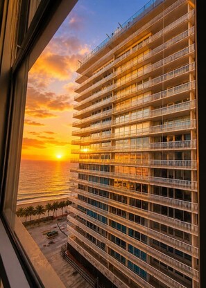 Ein Hochhaus mit mehreren Balkonen, Blick auf den Sonnenuntergang über dem Meer und einem klaren Himmel.