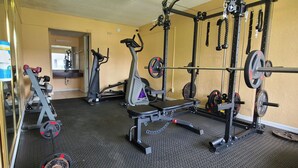 A gym with cardio equipment, weightlifting stations, and a mirror. - Paramount Lakeside Inn & Suites (Lakeland)
