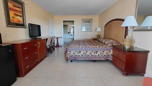 A hotel room with a bed, a television, a desk, and a chair. - Paramount Lakeside Inn & Suites (Lakeland)