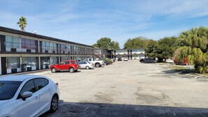 A motel with multiple-story buildings, a parking lot with several cars, and palm trees. - Paramount Lakeside Inn & Suites (Lakeland)