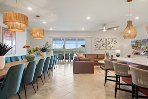 A modern kitchen with a dining area, large windows, and a view of the outdoors.