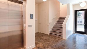 Ein modernes Interieur mit Treppe, Aufzug und einer Tür mit Schilder.