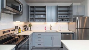 Eine moderne Küche mit grauen Schränken, einem Edelstahl-Kühlschrank, einer Spülmaschine und einem eingebauten Backofen.