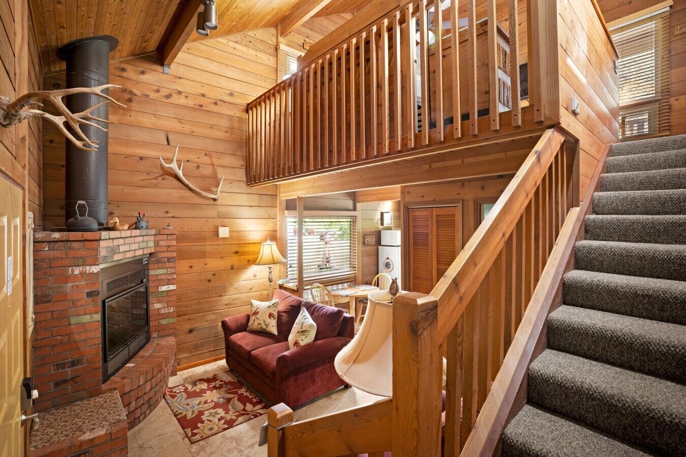 A wooden interior with a fireplace, a staircase, and a cozy seating area.