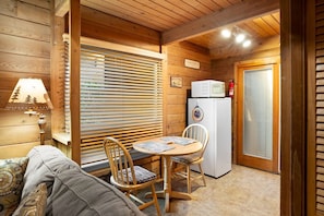 A cabin interior with a wooden ceiling, a table with chairs, a refrigerator, and a lamp. - Romantic Cabin next to Slide Rock - Morning Glory (Sedona)