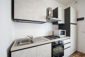 A modern kitchen with a stainless steel sink, gas stove, microwave, and built-in oven.