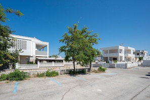 A residential area with modern buildings, a parking lot, and a tree.