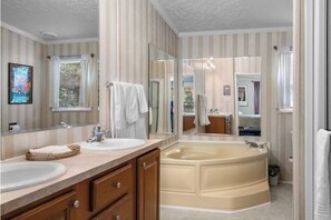 Ein Badezimmer mit zwei Waschbecken, einer Badewanne und einem großen Spiegel.