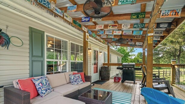 A covered porch with a sofa, grill, and various license plates. - Atchley Hill Farm (Knoxville)