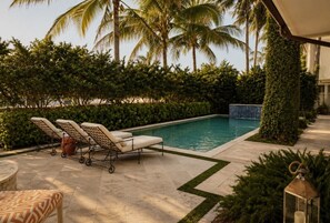 Ein Poolbereich mit Liegestühlen, einem kleinen Tisch und einer Laterne.