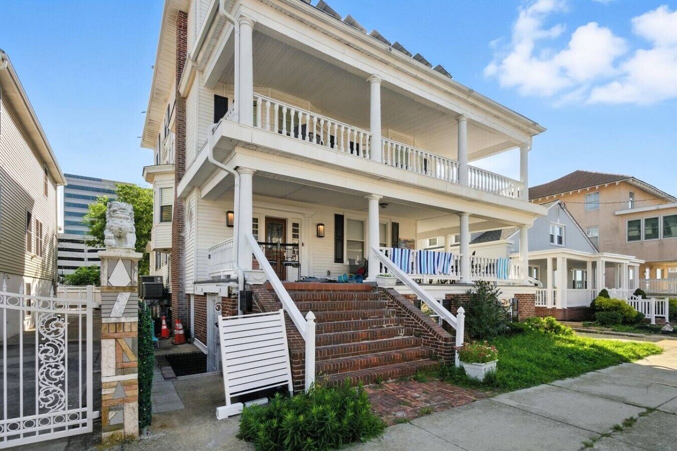 A two-story house with a front porch, a staircase, and a gated entrance.
