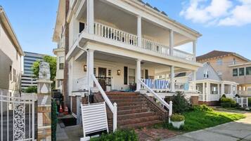A two-story house with a front porch, a staircase, and a gated entrance.