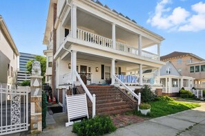 Ein zweistöckiges Haus mit Veranda, Treppe und einem eingenetzten Eingang.