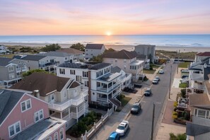 Un quartier résidentiel avec des maisons, une rue et un coucher de soleil sur l’océan.