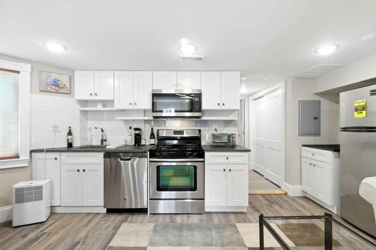 A modern kitchen with white cabinetry, stainless steel appliances, and a central island.