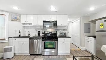 A modern kitchen with white cabinetry, stainless steel appliances, and a central island.