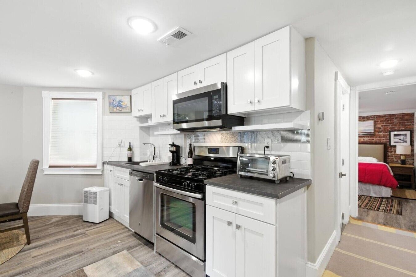 A compact kitchen with white cabinets, a microwave, a stove, and a toaster.