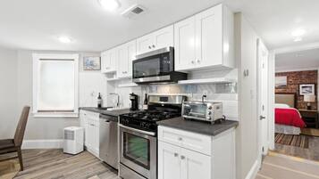 A compact kitchen with white cabinets, a microwave, a stove, and a toaster.