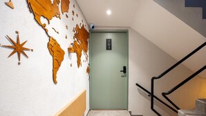 Eine Treppe führt zu einer Tür mit einer Nummernschild, eine Wand mit einem Kartenmuster und einem sternförmigen Gegenstand.