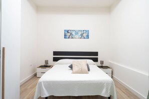 Ein Schlafzimmer mit einem Bett, zwei Nachttischen, einem Wandbild und Holzboden.