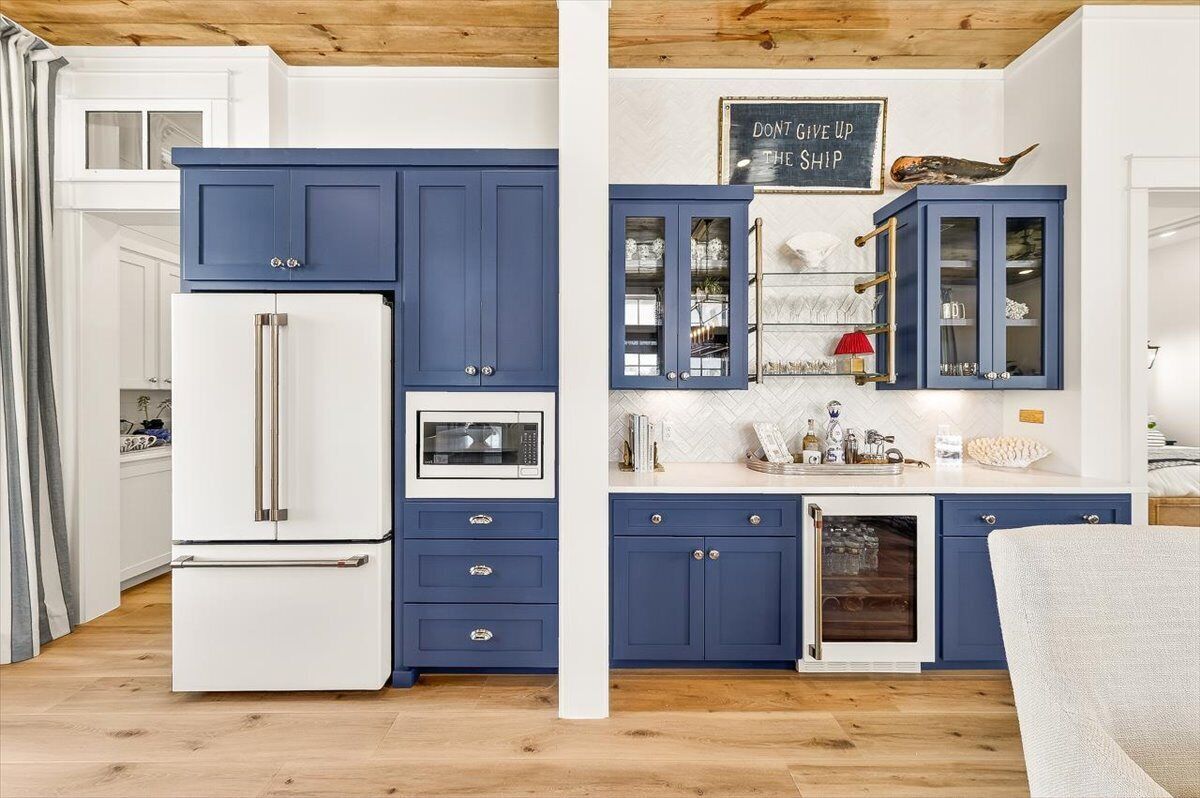 A kitchen with blue cabinets, a white refrigerator, and a chalkboard with motivational writing.