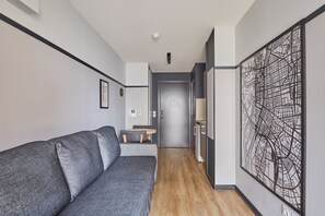 Ein Flur mit einem grauen Sofa, einem kleinen Tisch und einem Wandbild.