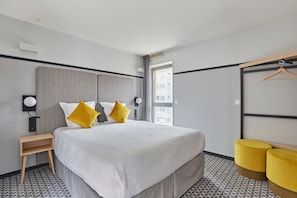 Une chambre d’hôtel moderne avec un grand lit, des tables de chevet, un miroir et une vue sur la ville.
