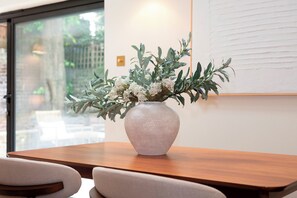 A wooden table with a white vase containing green foliage and white flowers. - Luxury 2BR Apartment, Garden & Central Access - Pass the Keys (London)