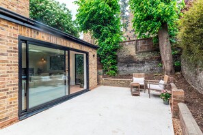 A patio with a glass door, brick walls, and outdoor furniture. - Luxury 2BR Apartment, Garden & Central Access - Pass the Keys (London)