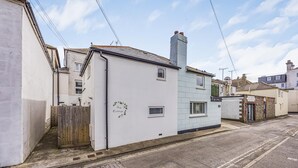 Uma rua estreita com um edifício branco na esquina, com a inscrição 'Ivy Cottage'.
