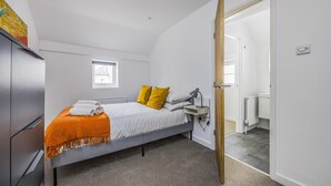 Quarto com cama, escrivaninha, radiador e armário.