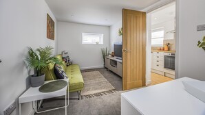 Um apartamento moderno com um sofá verde, uma pequena área de refeições e uma cozinha.