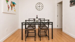 A dining area with a table and chairs, a wall clock, and a colorful abstract painting. - Buleria: The Charm and Essence of Jerez (Jerez de la Frontera)