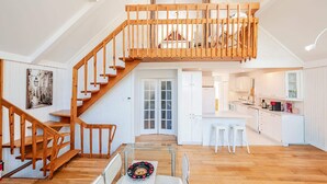 Een ruime loft met een houten trap, een eethoek en een keuken.