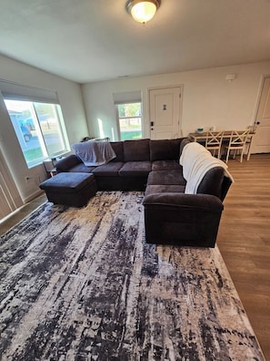 Ein Wohnzimmer mit Ecksofa, Couchtisch und einem gemusterten Teppich.