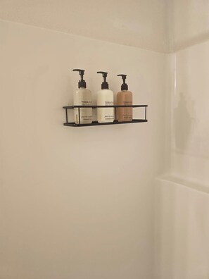 A bathroom with a black shelf holding three bottles of TerraPure Spa Collection products. - Earl Street Retreat Unit A (Stanfield)