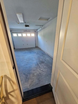 Eine Garage mit Betonboden, weißen Wänden und einer Tür zu einem Flur.